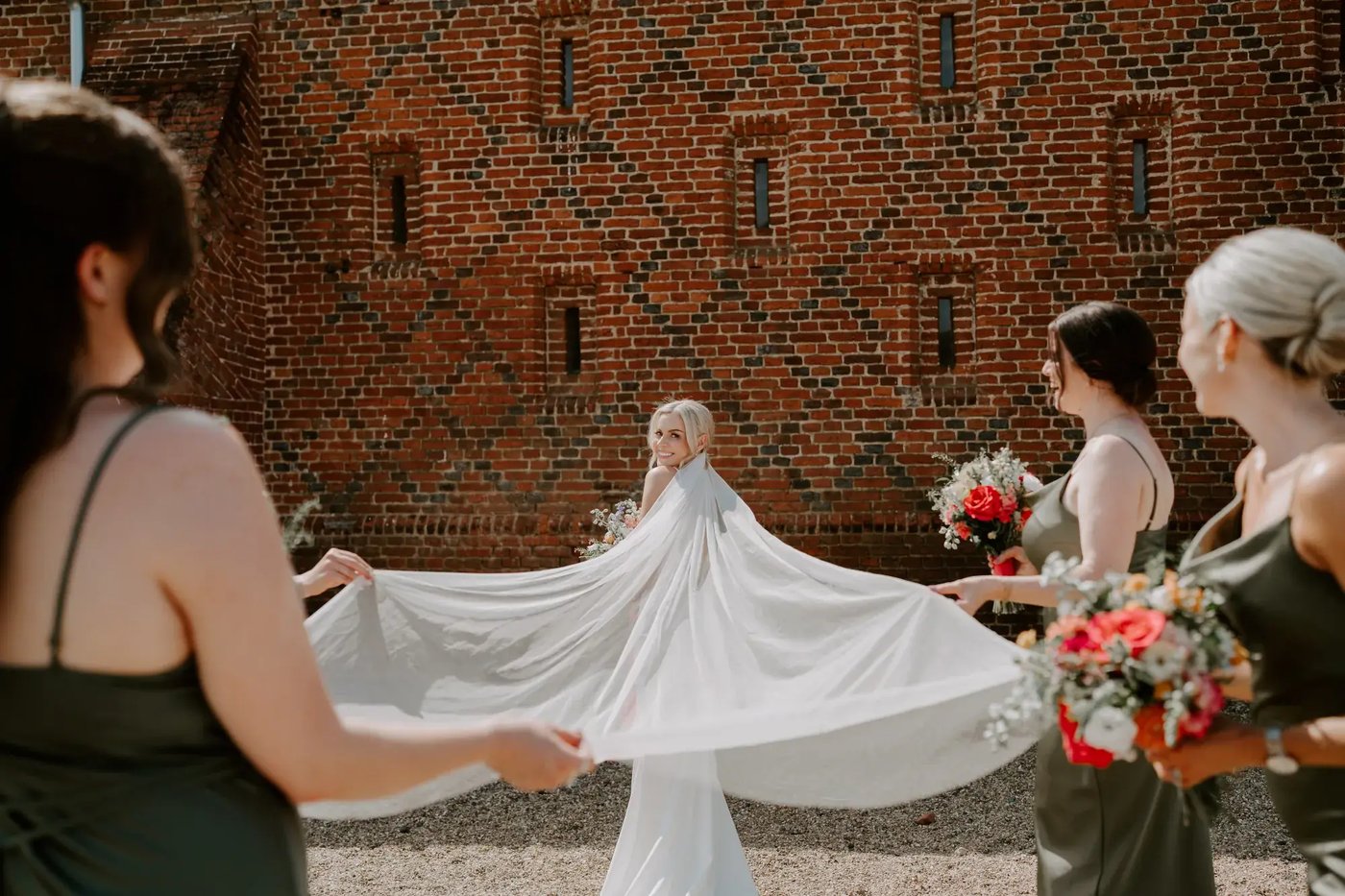 Bride and bridesmaids posing for photo outside of the barn at Copdock Hall