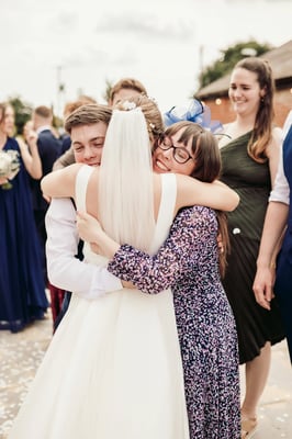 Bride hugging wedding guests outside at Copdock Hall