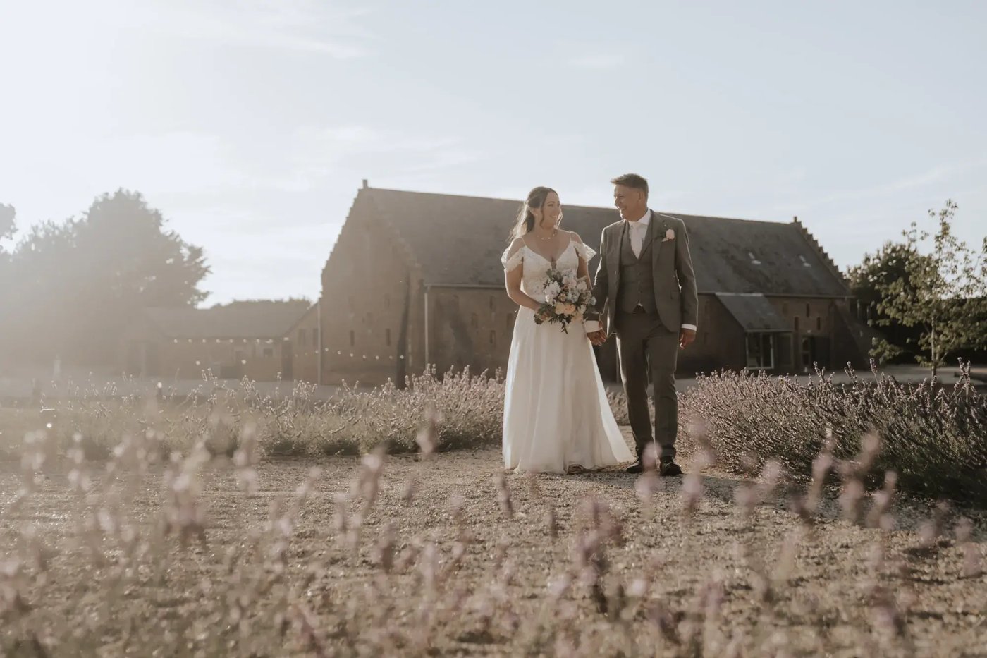 Couple holding hands walking through the grounds at Copdock Hall