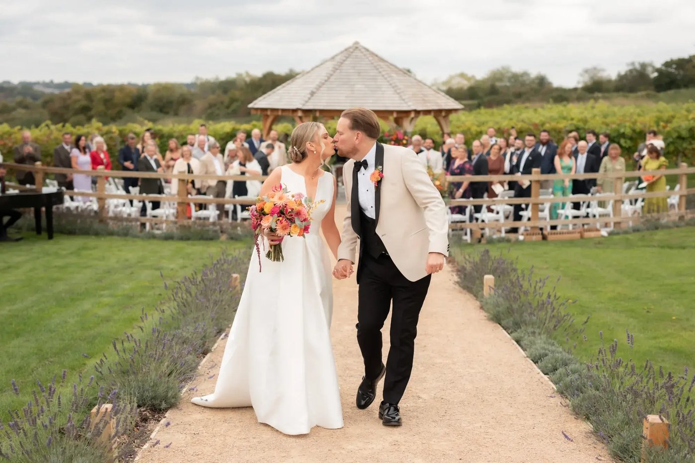 Couple kissing as they walk away from outdoor ceremony space at Copdock Hall