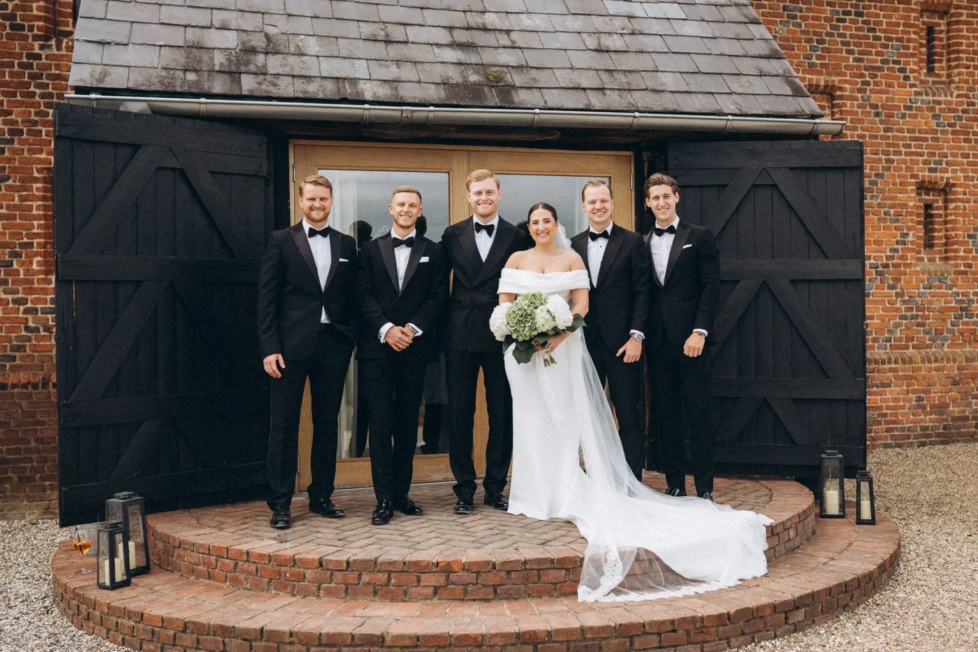 Couple and groomsmen posing outside of Copdock Hall