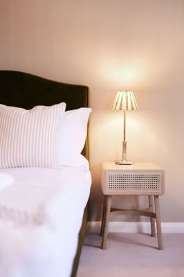 Bedside table with lamp in accommodation at Copdock Hall