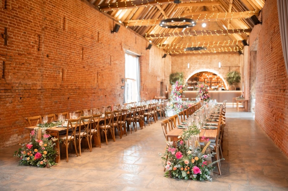 Copdock hall long tables set up in barn with bright floral décor